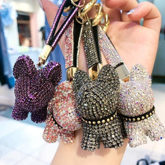 Dieser Schlüsselanhänger in Form eines Hundes, verziert mit funkelnden Diamanten, ist ein echter Hingucker. Das liebevolle und luxuriöse Design macht ihn zum perfekten Accessoire für Taschen, Autoschlüssel oder als Geschenk.