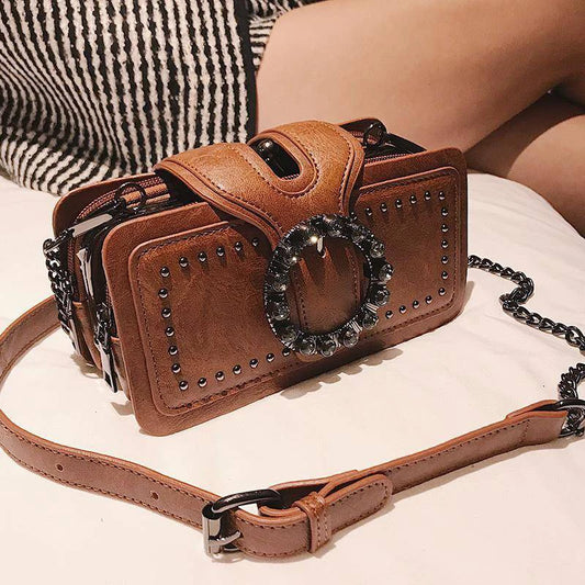 Trendige Damen Handtasche mit runder Strass-Schnalle, Punk-Nieten und Top-Handle. Stylisch als Schulter- oder Crossbody Bag tragbar.

